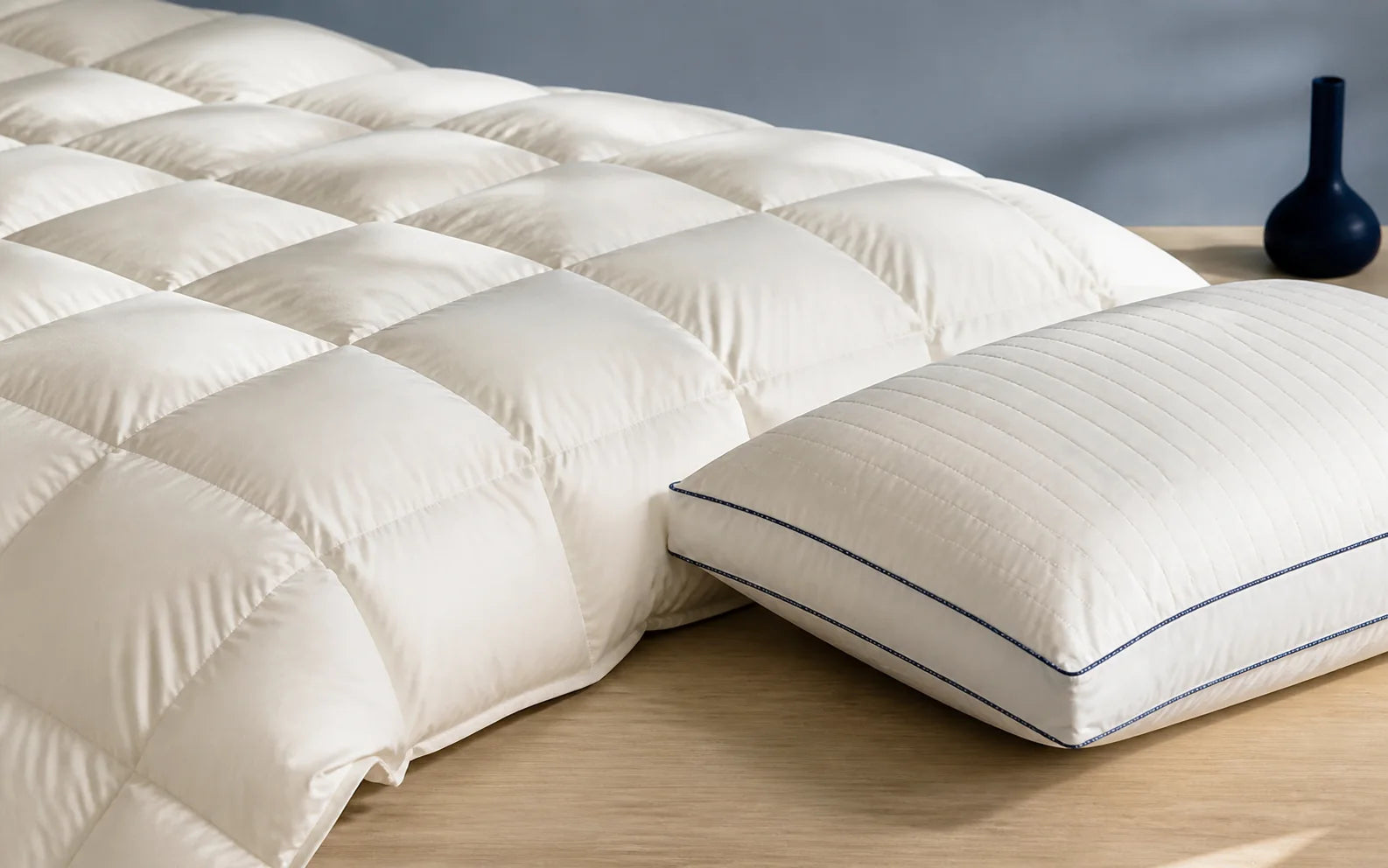 White baffle-box comforter beside a quilted gusseted pillow with navy piping